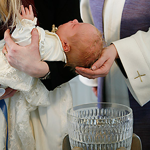 Pappi kastaa lasta ristiäisissä. Hauhon seurakunta.